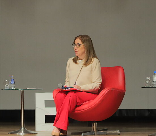 Imagem de 3 professores conversando no palco de uma palestra.