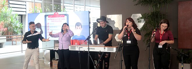 na imagem, cinco pessoas com instrumentos musicais se apresentam
