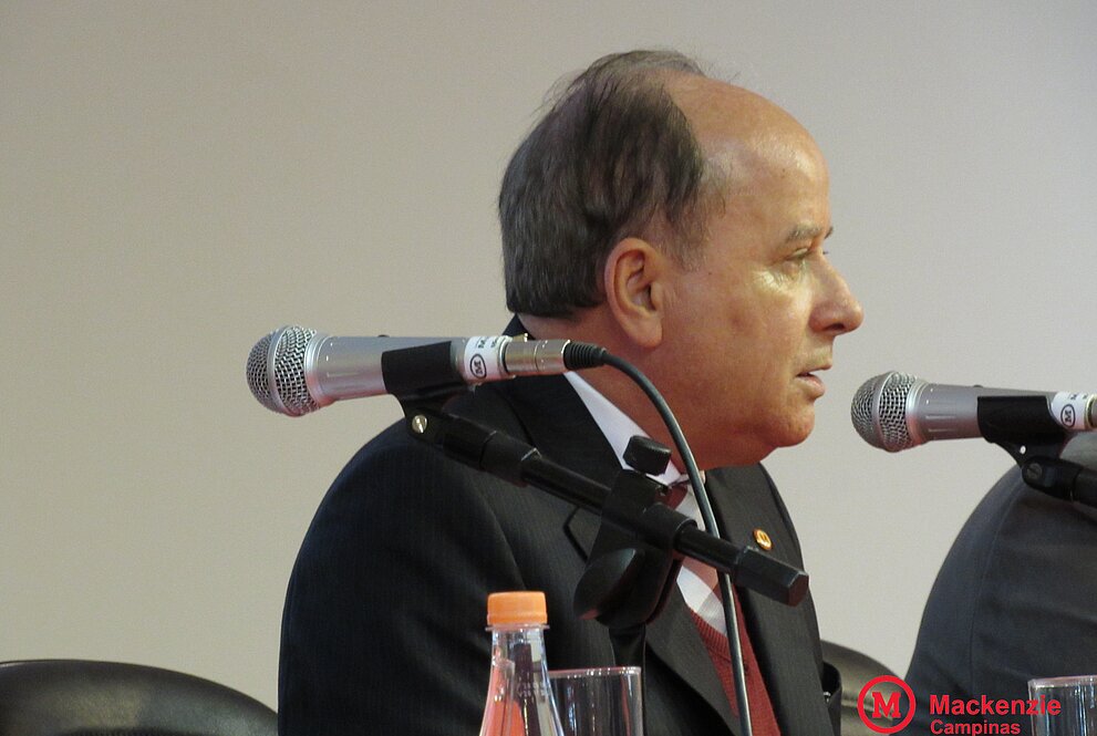 Homem sentado falando ao microfone