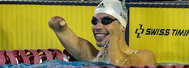 Daniel Dias comemorando o tempo dos 100m livre dentro da água, com óculos e touca de natação.