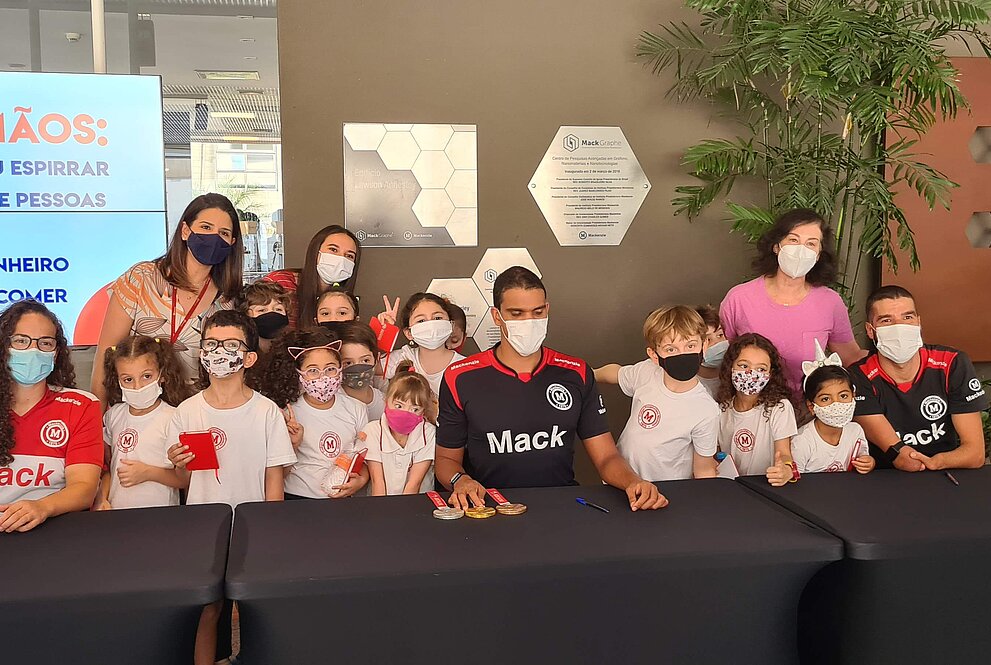 um grupo composto por crianças e adultos posam para foto