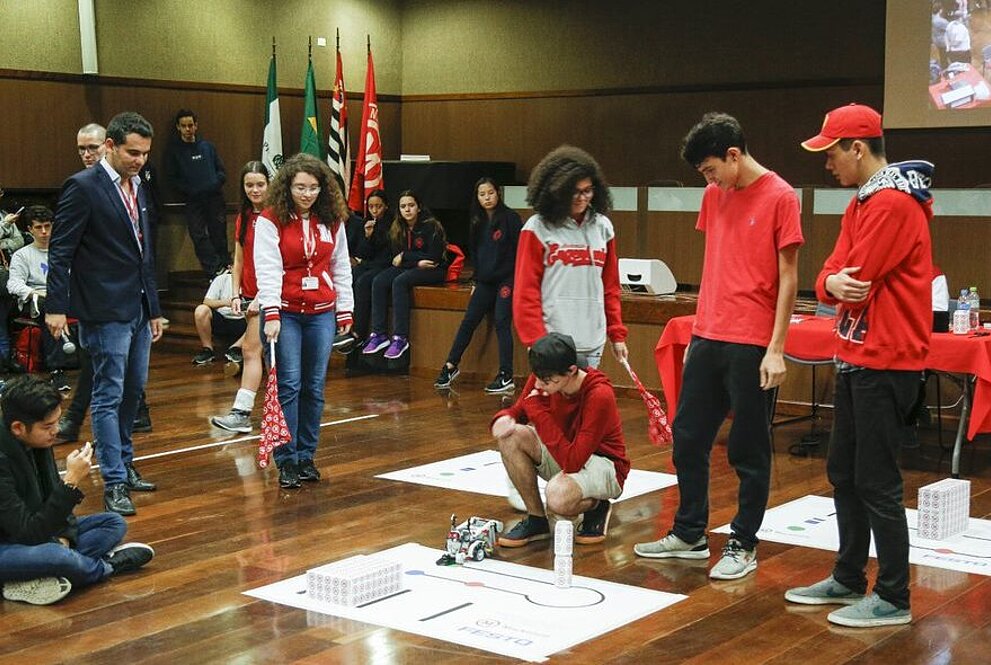 Equipe testando seu robô ao redor das pessoas, ao mesmo tempo que estão sendo avaliados.