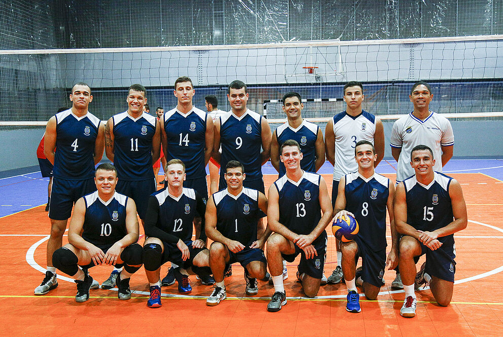 Competidores da Escola Naval posando para foto, em frente à rede de voleibol.