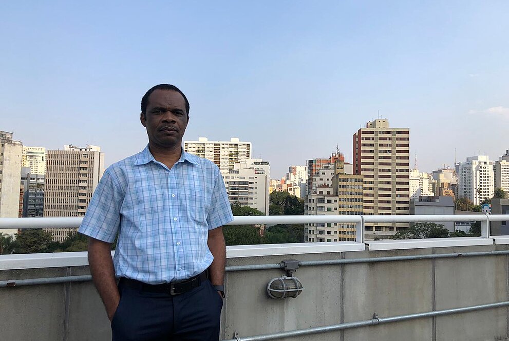 Homem em pé com a cidade de SP ao fundo