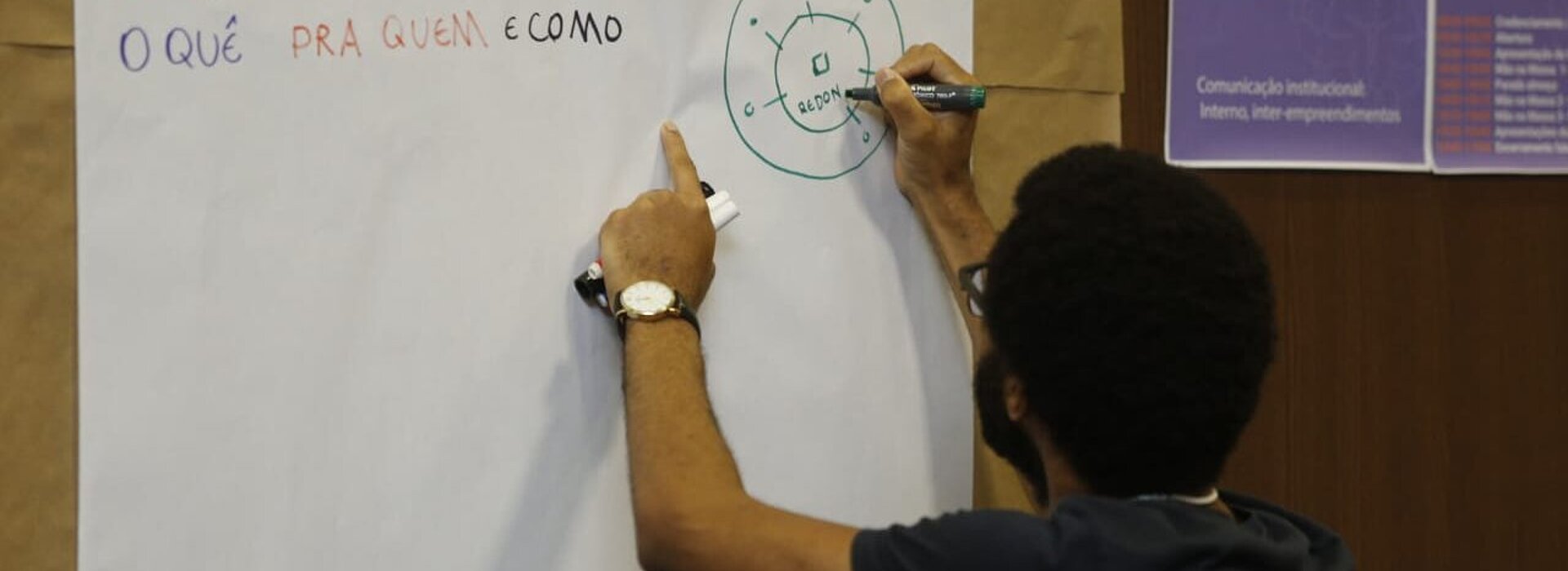 homem escreve em cartolina fixada na parede