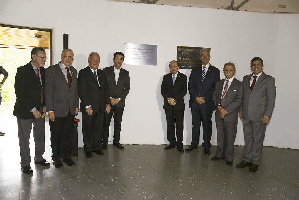 Vários homens brancos em pé exibindo placa de metal