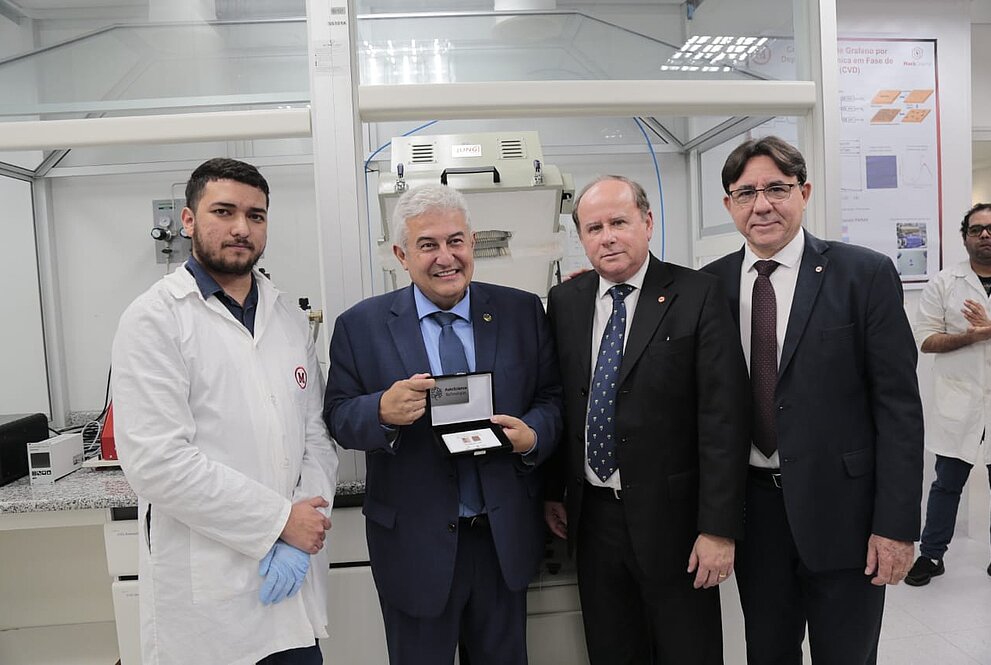 Quatro homens em pé dentro de um laboratório