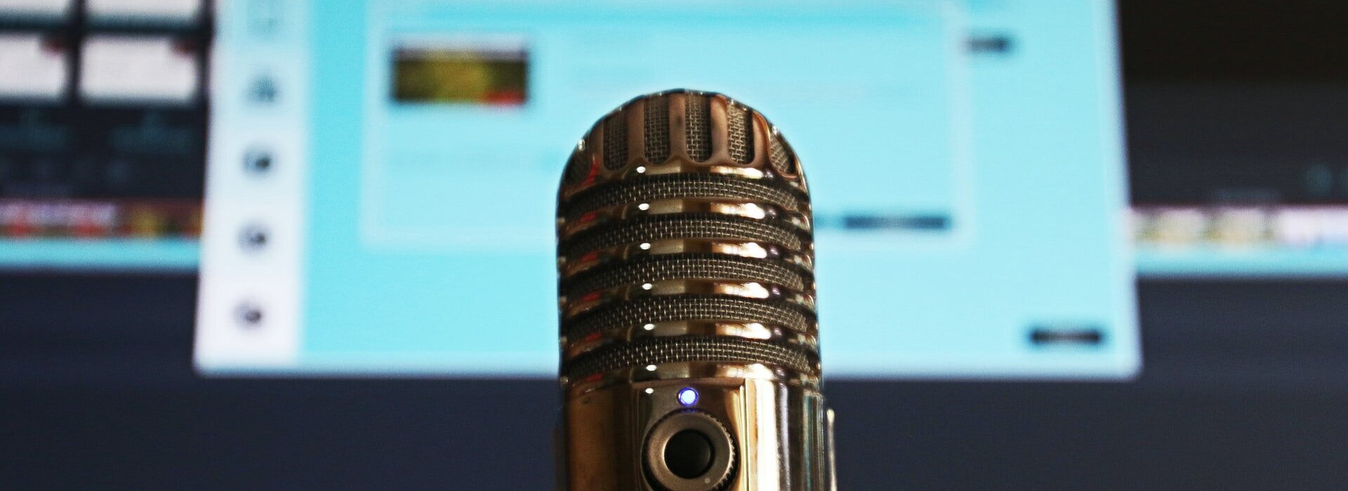 microfone em primeiro plano com uma tela de computador azulada desfocada ao fundo