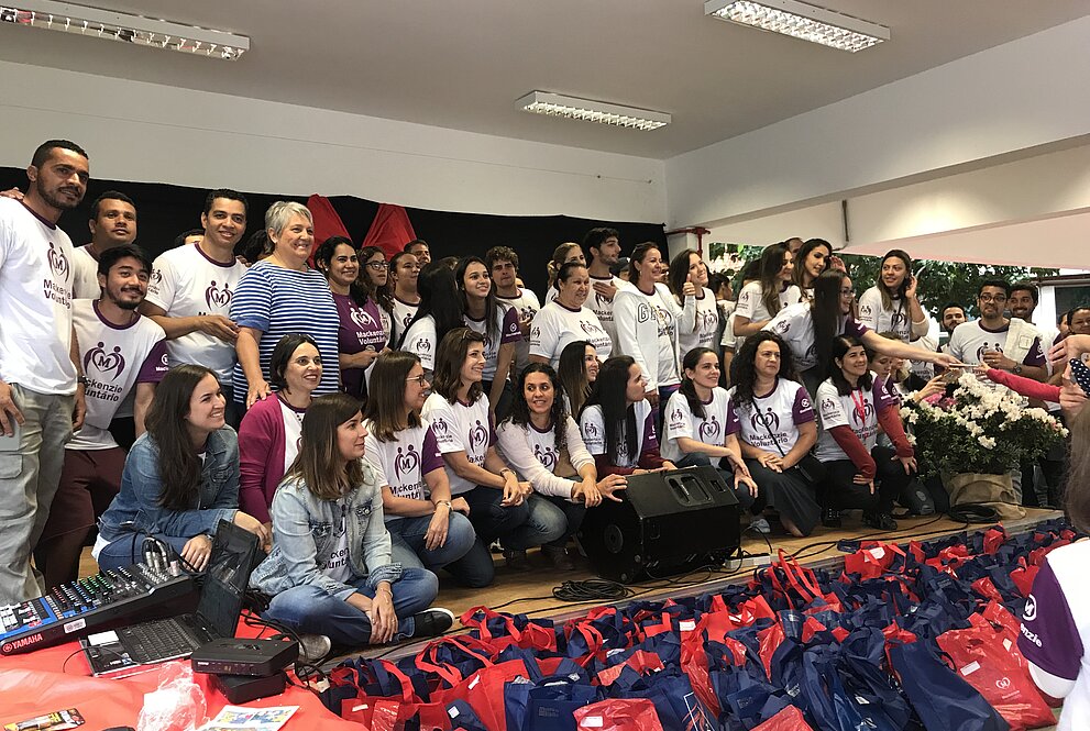 várias pessoas voluntárias do mackenzie voluntário tamboré em frente à arrecadação 
