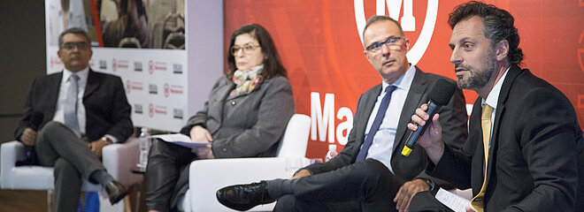 especialistas debatem no palco. Plateia cheia