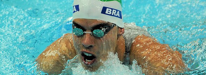 Nadador na piscina competindo com uma touca do Brasil