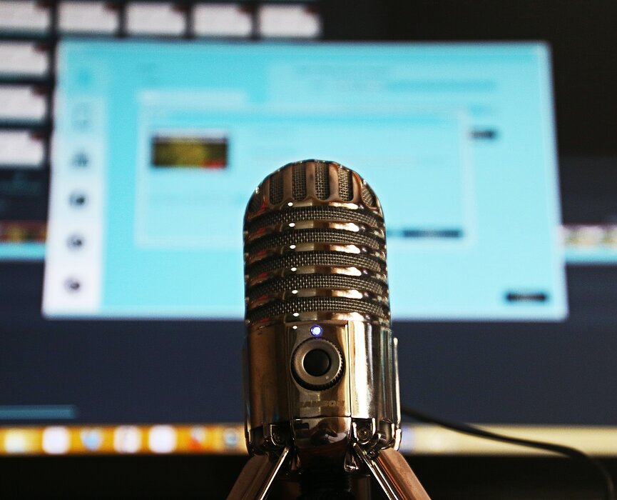 microfone e computador aberto em página de edição de um podcast 