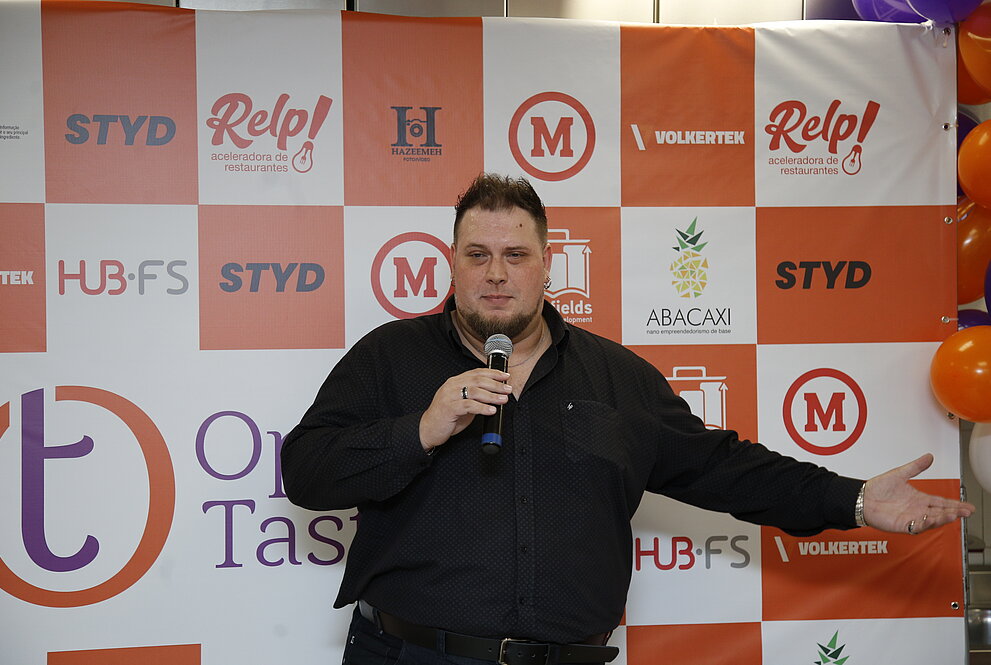 Homem discursa de pé com microfone na mão
