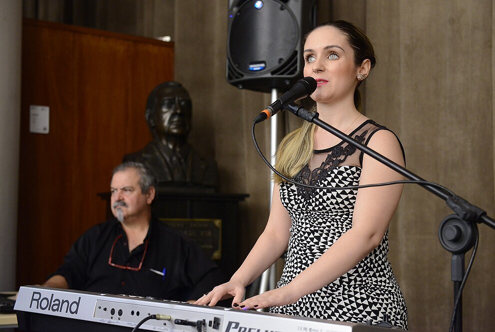 mulher de pé toca teclado enquanto canta