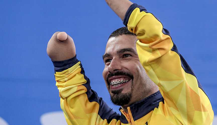 Daniel Dias com os braços levantados, comemorando. 