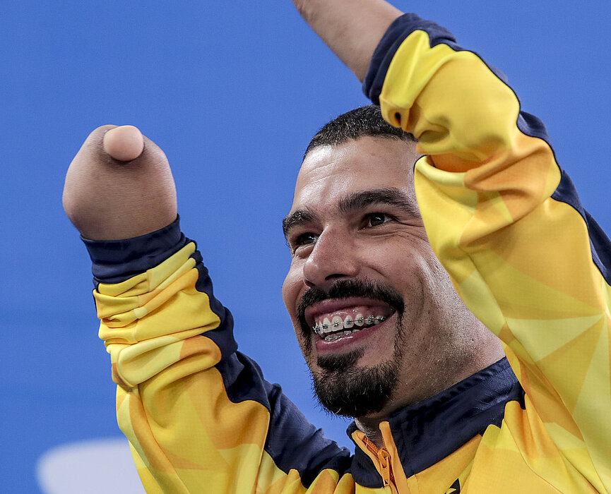 Daniel Dias com os braços levantados, comemorando.