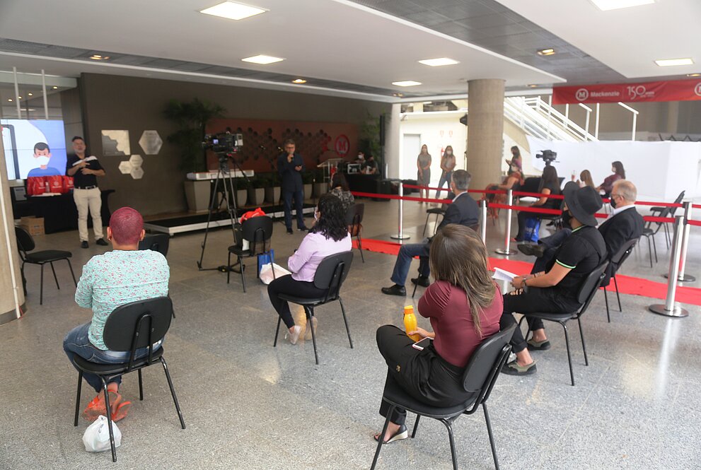 pessoas sentadas acompanham o evento