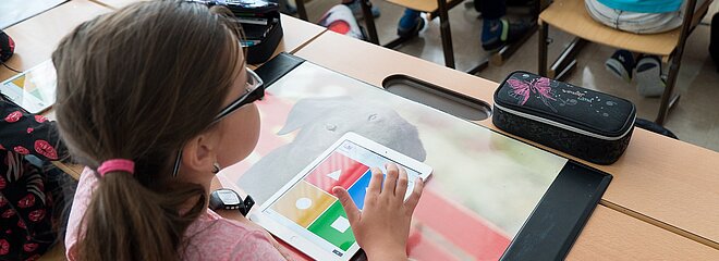 Garota com um tablet fazendo atividade em sala de aula