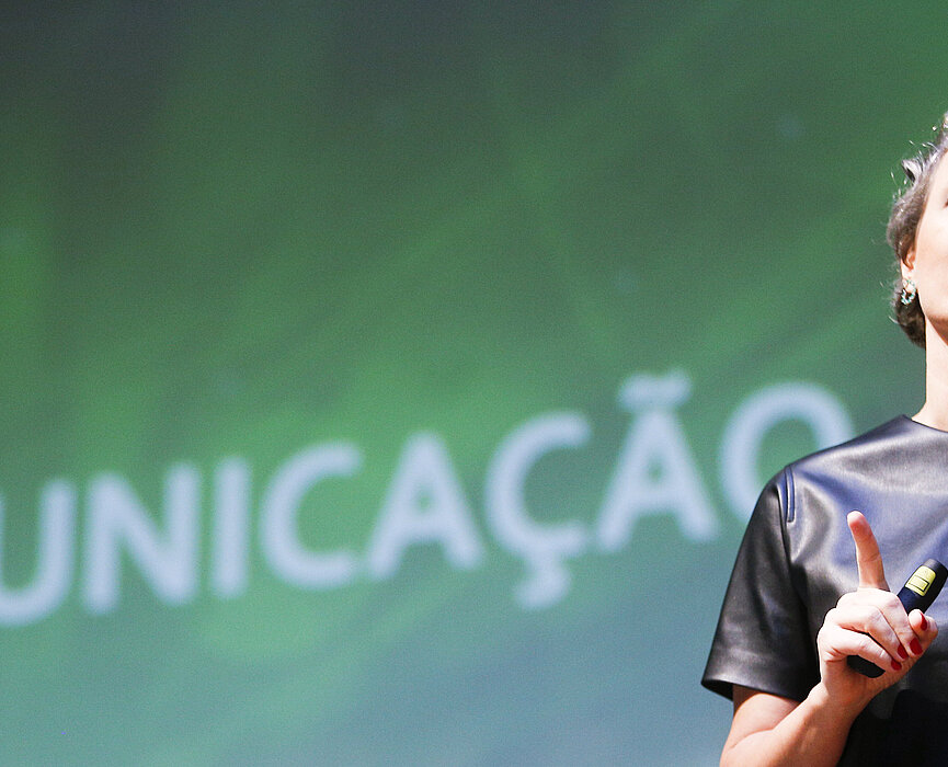 Daniela Cachich no palco com telão ao fundo