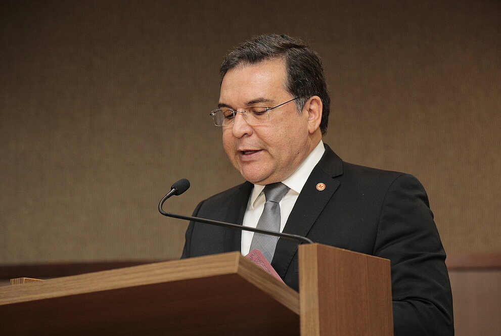 Homem de terno preto falando ao microfone em um púlpito