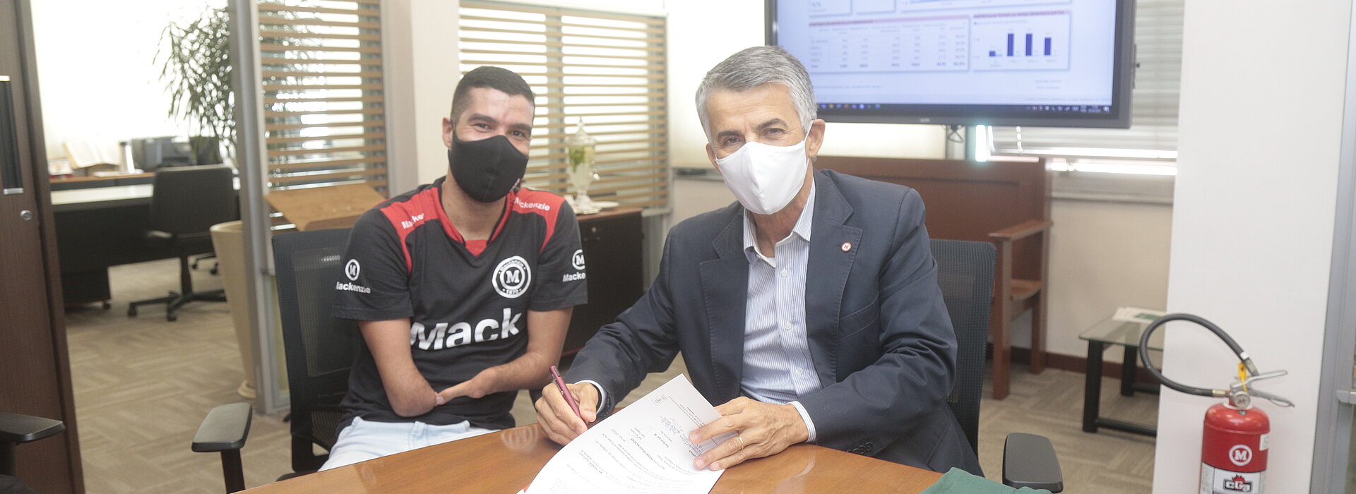 Dois homens sentados assinando um contrato