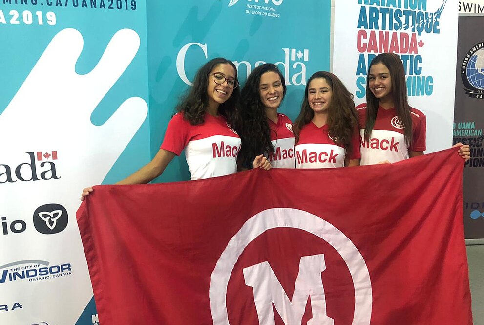 Quatro meninas seguram bandeira com o símbolo do Mackenzie