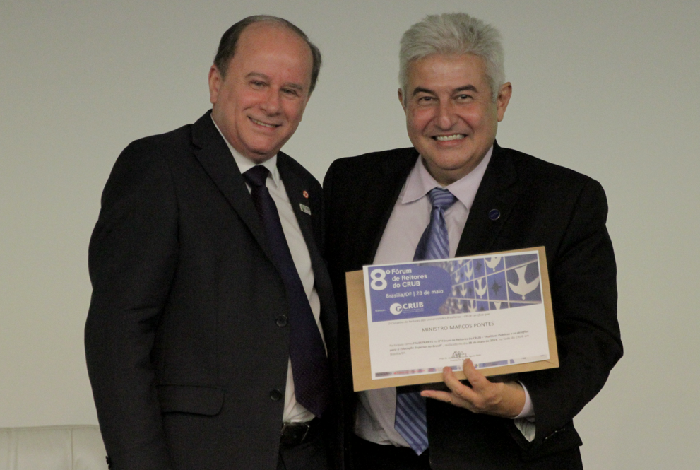 Dois homens sorrindo para foto estando um segurando um certificado