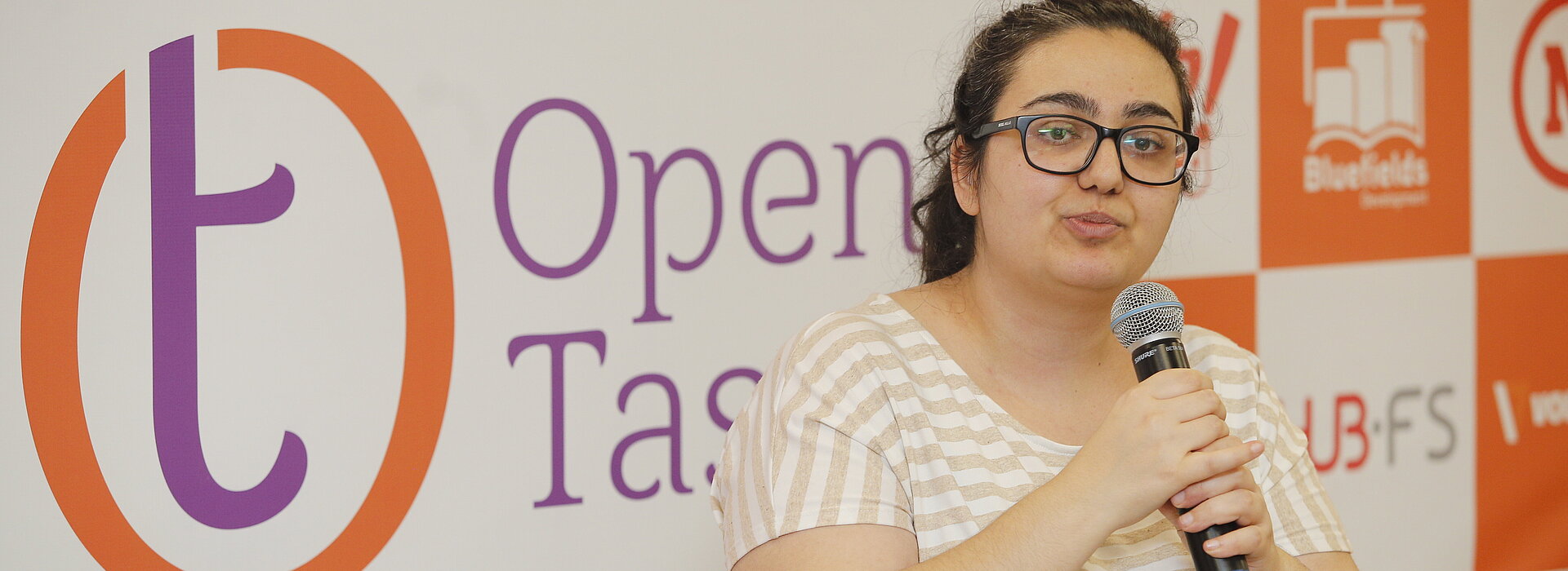 Mulher discursa de pé com microfone na mão