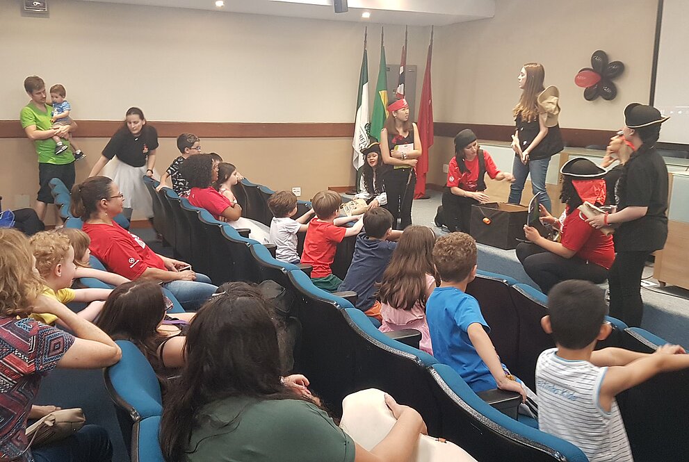 Crianças assistem a adultos em cena teatral