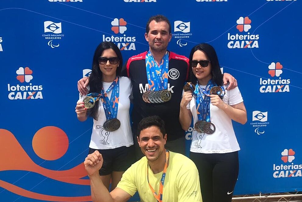 Felipe com o treinador Rafael e as atletas de natação Marina e Fernanda