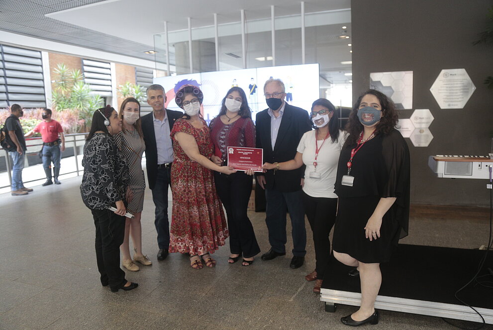 seis mulheres e dois homens de pé posam para foto com premiação