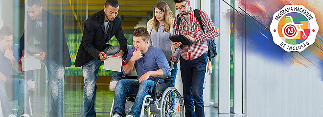 Na foto, um homem na cadeira de rodas conversa com mais dois homens e uma menina. Eles estão mexendo em tablets. No lado superior direito, está o logo do Programa Mackenzie de Inclusão, que tem como imagem uma cadeira de rodas com um M de Mackenzie no meio. 