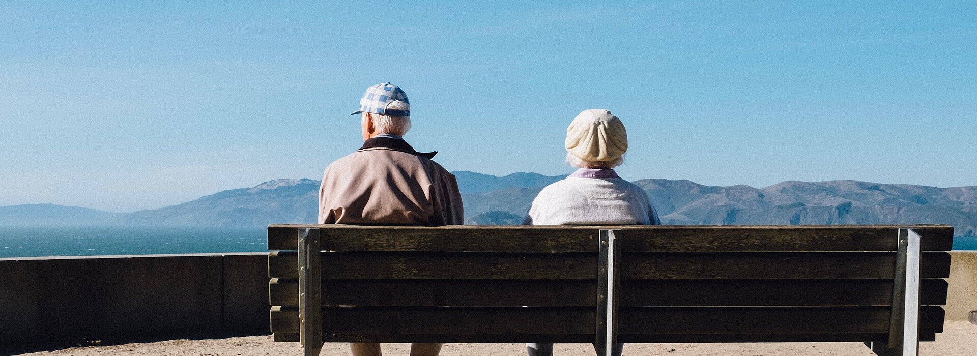 Idosos sentados em um banco e observando o horizonte.