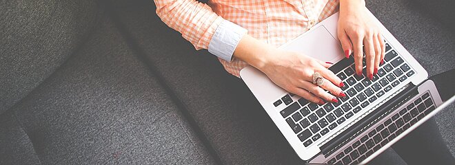 aluna sentada no sofá com laptop no colo