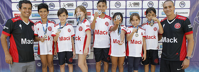 Alunos e professores do Colégio Mackenzie posando para foto estando os alunos com as medalhas em suas mãos