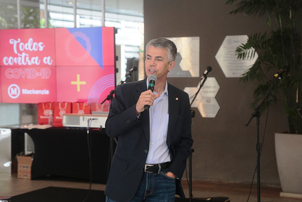 homem branco de terno e segurando microfone discursa