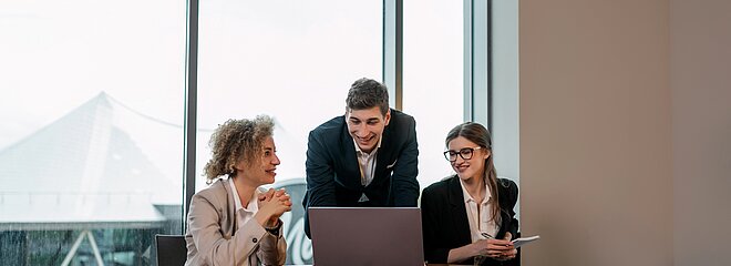 Três pessoas sentadas na mesa com um computador.