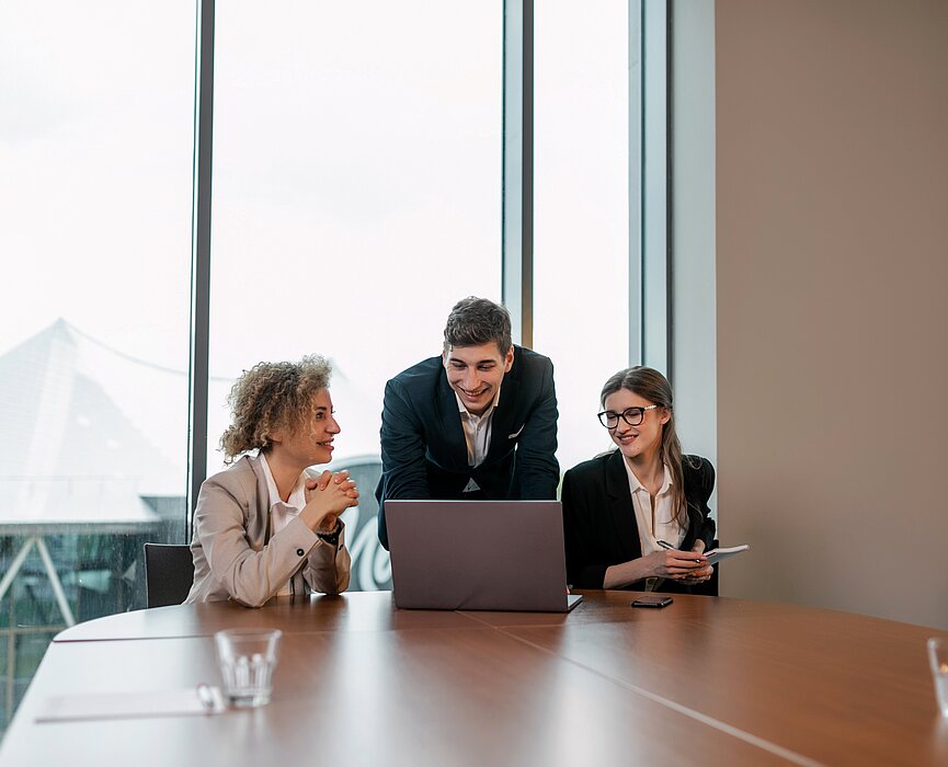 Três pessoas sentadas na mesa com um computador.