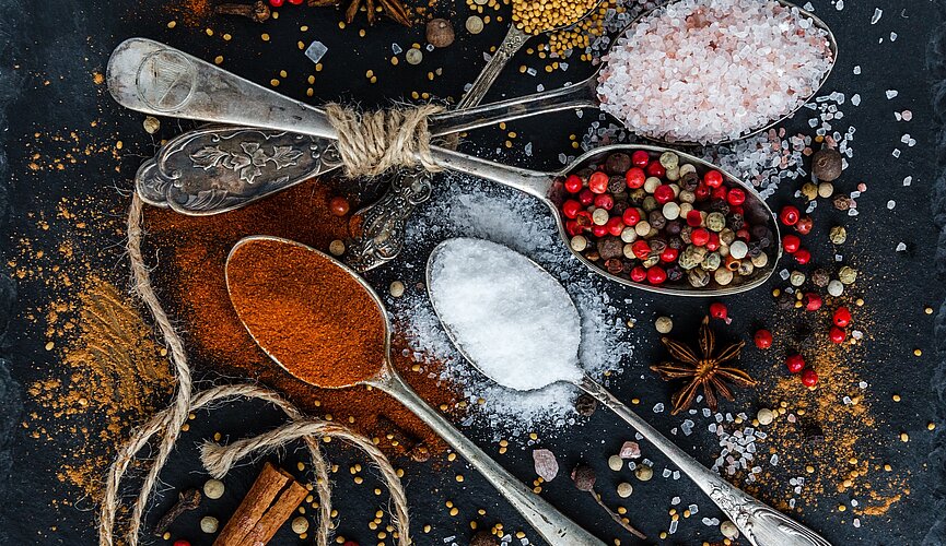 alimentos e temperos espalhados em cima de uma mesa e sobre colheres