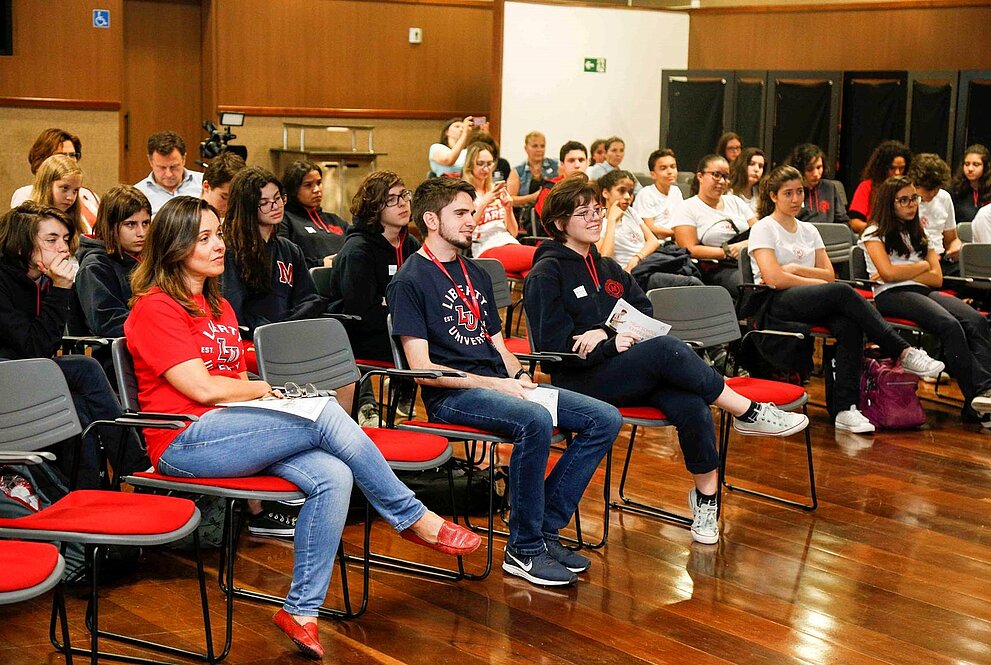 Várias pessoas sentadas numa plateia assistindo às palestras