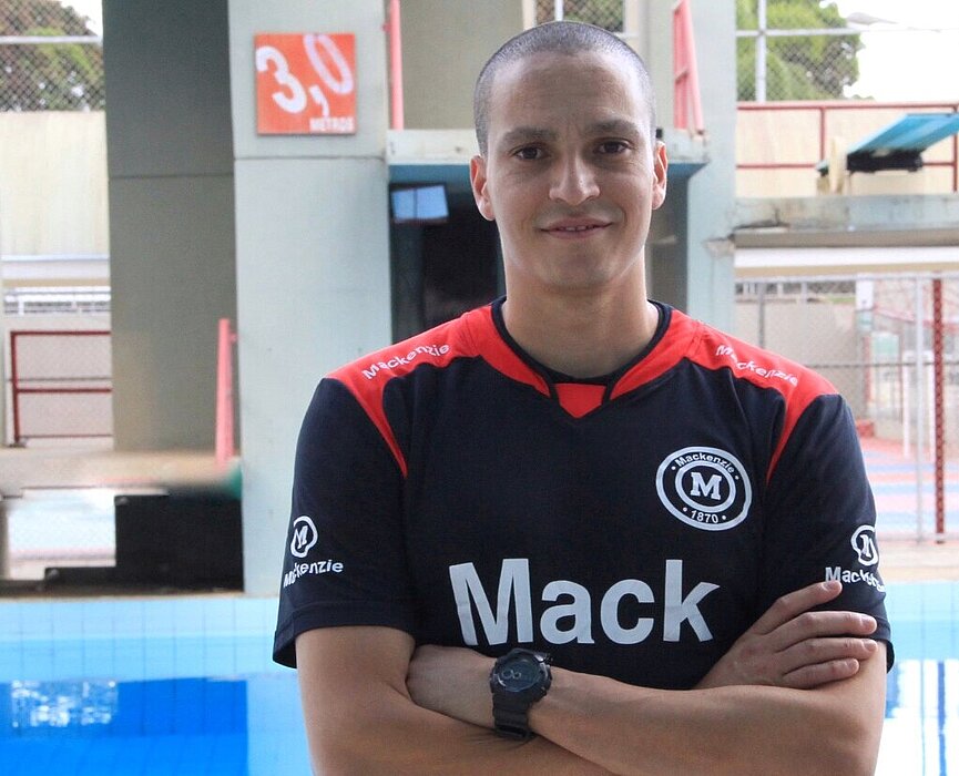 Atleta César Castro parado em frente a piscina do Colégio Mackenzie Brasília