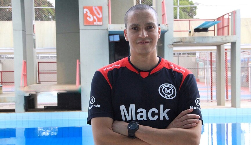 Atleta César Castro parado em frente a piscina do Colégio Mackenzie Brasília