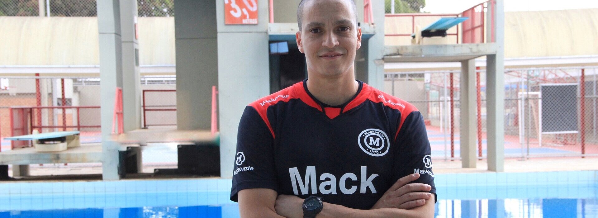 Atleta César Castro parado em frente a piscina do Colégio Mackenzie Brasília