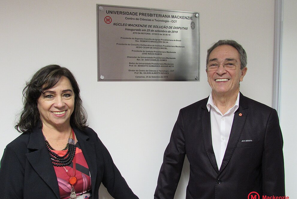 casal de mãos dadas ao lado da placa de aço de inauguração