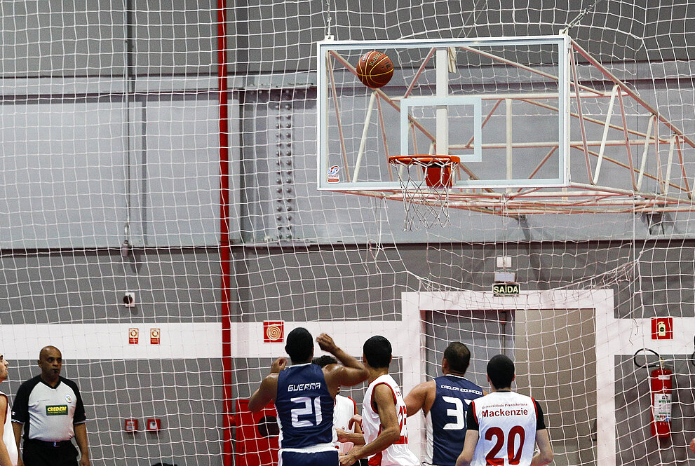 Escola Naval e Mackenzie em final de jogo, observando se a bola vai cair ou não na cesta de basquete.. 