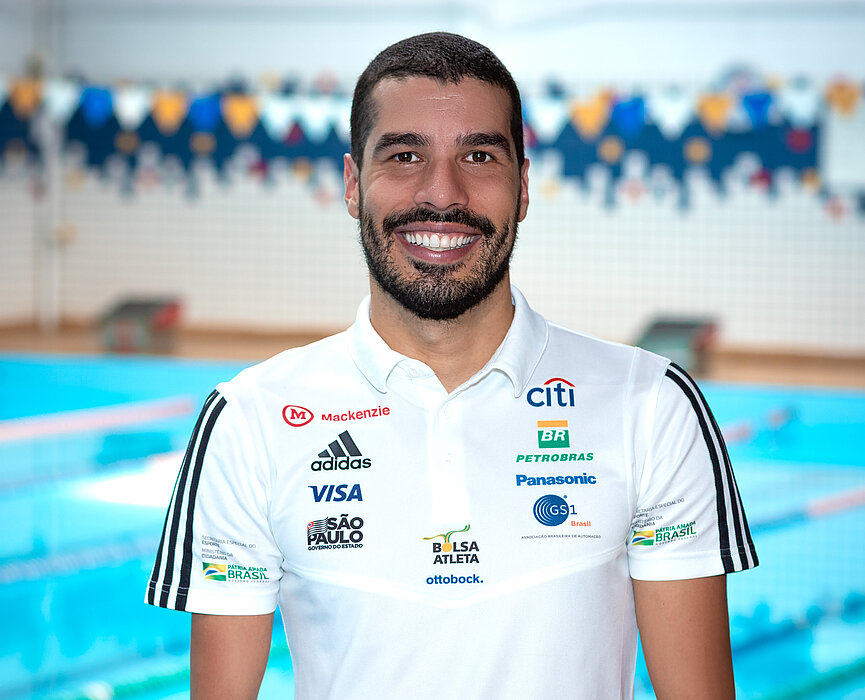 Homem sorridente parado em frente a uma piscina