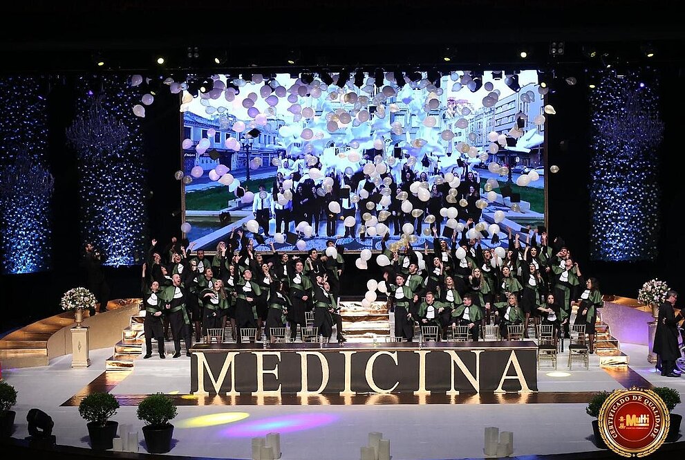 formandos sentados no palco com telão ao fundo