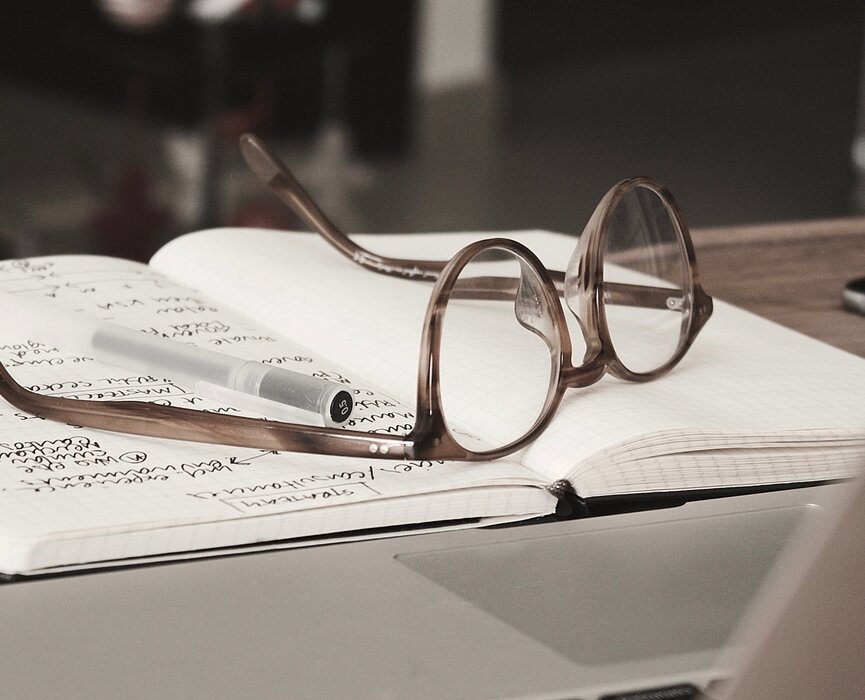 óculos e caderno em cima de uma mesa