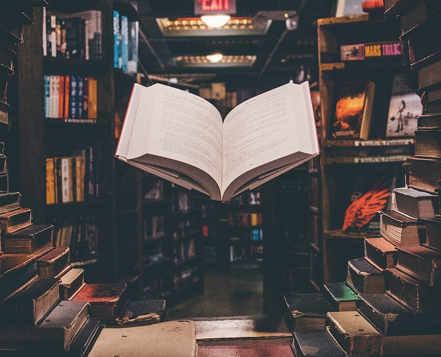 livro aberto em meio a uma biblioteca