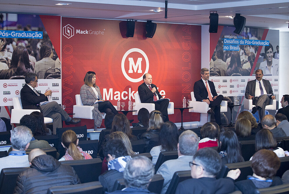 autoridades debatendo no palco com plateia cheia